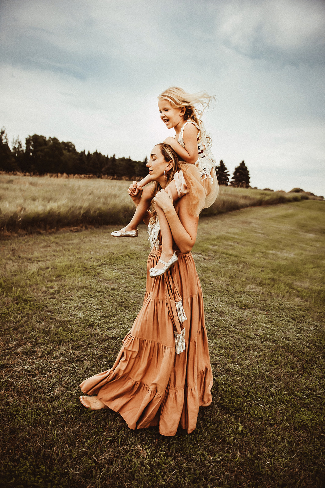 mother holding daughter on her shoulders walking around their acreage 