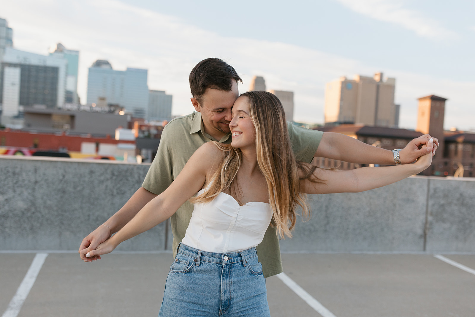 a couple takes engagement photos with the Kansas City skyline