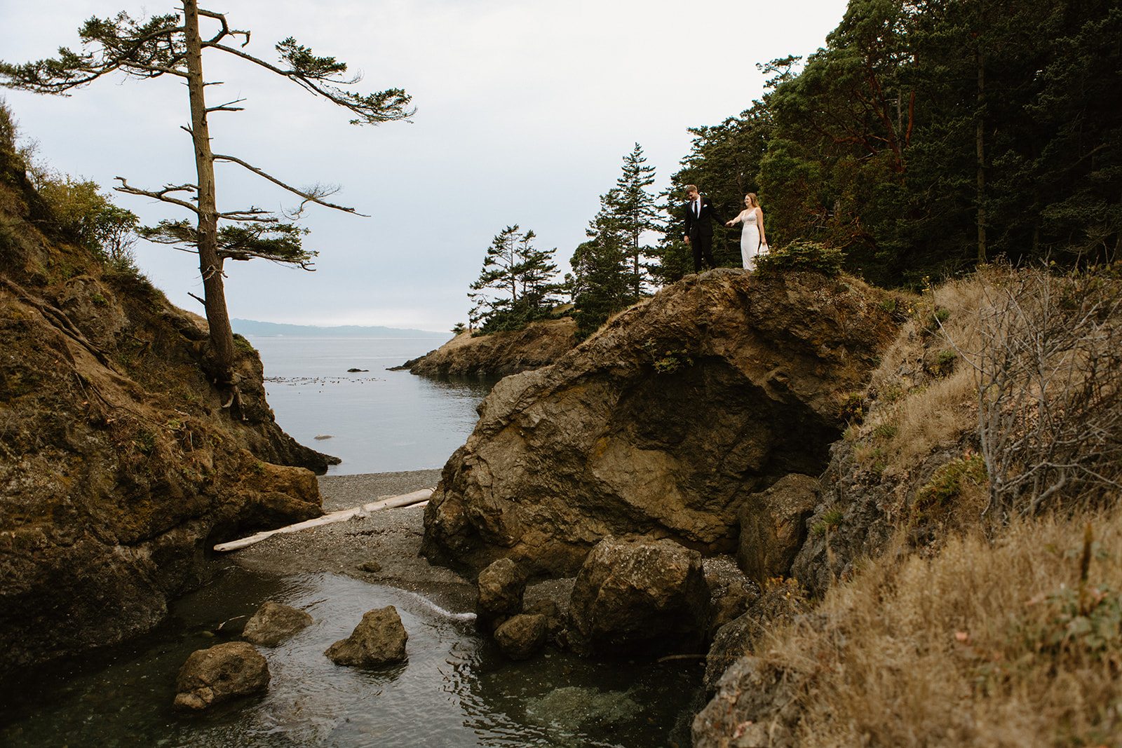 A forested, coastal photoshoot with a couple in their wedding attire at Deception Pass in Washington state.