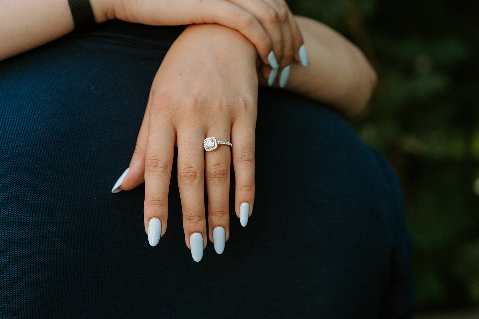 a hand resting on the back of a shoulder showing off a ring.