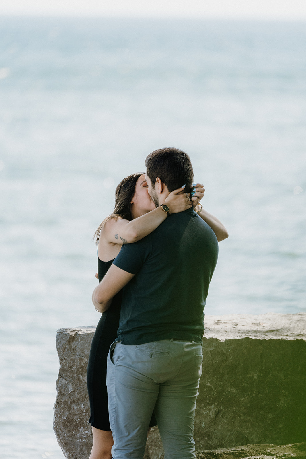 Woman kissing man by the water.