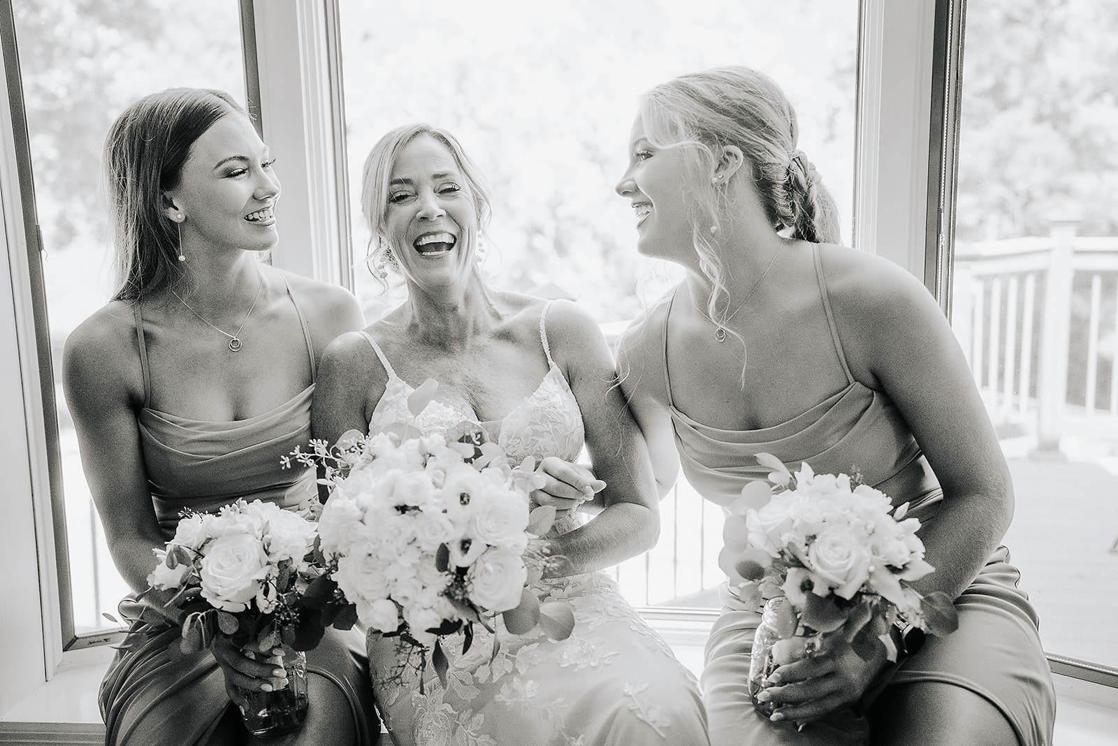 Black and white of bride with grown daughters laughing