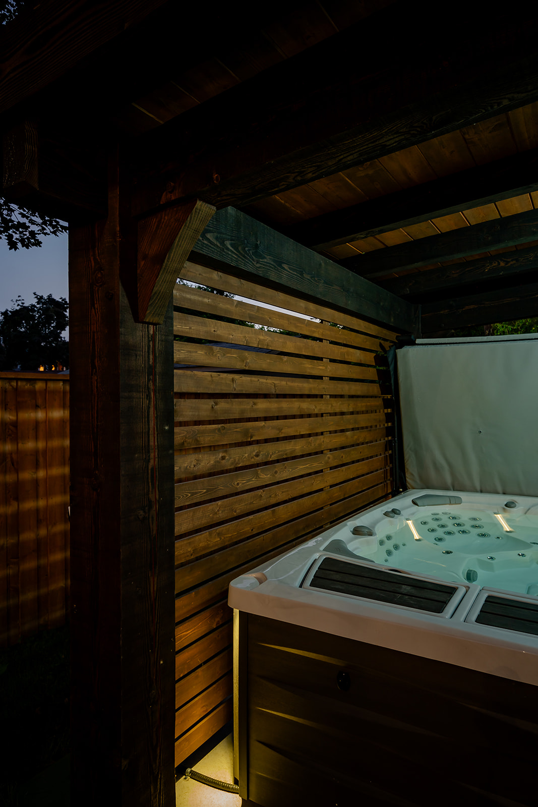 A jacuzzi that's on underneath a wooden canopy.