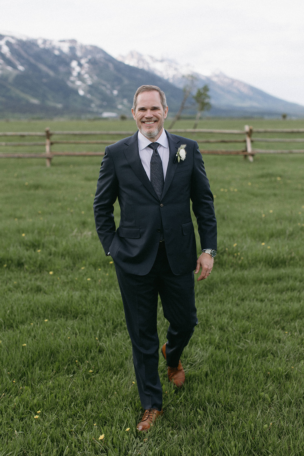 A timeless wedding portrait of a groom dressed in a black tailored suit adorned with a white boutonniere on his lapel.