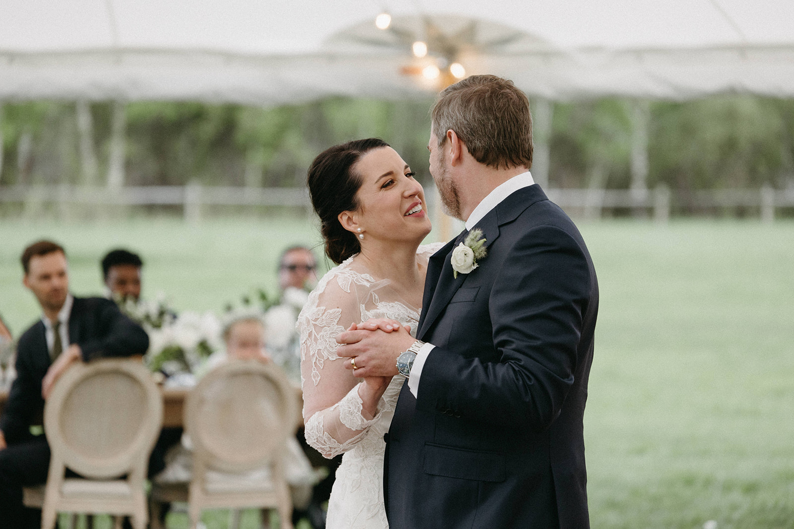 A bride, wearing a Bella Bianca Bridal Couture white wedding dress, shares a first dance with her husband. 
