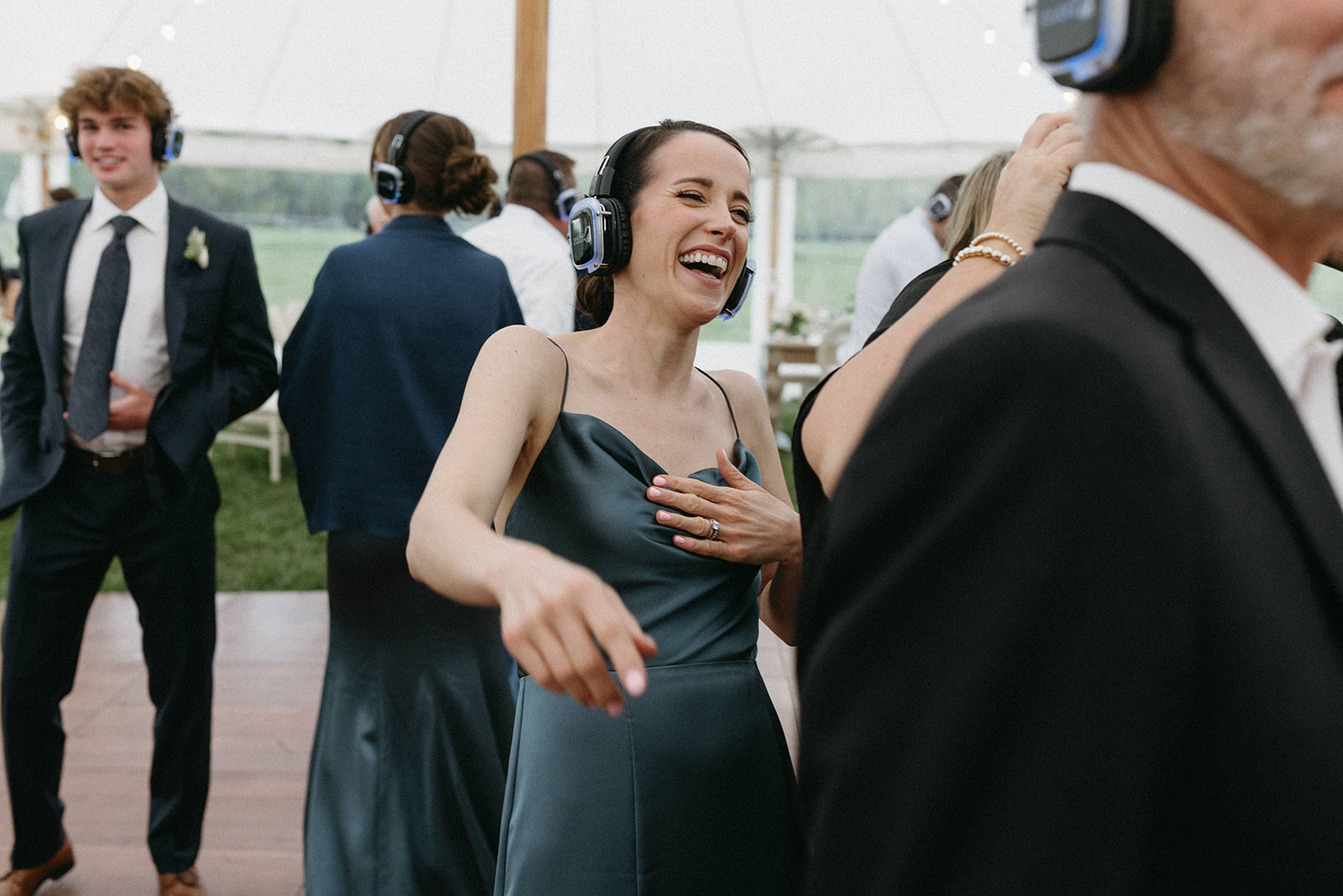 A bridesmaid wearing a slate blue bridesmaid dress is dancing with other wedding guests during a silent disco reception

