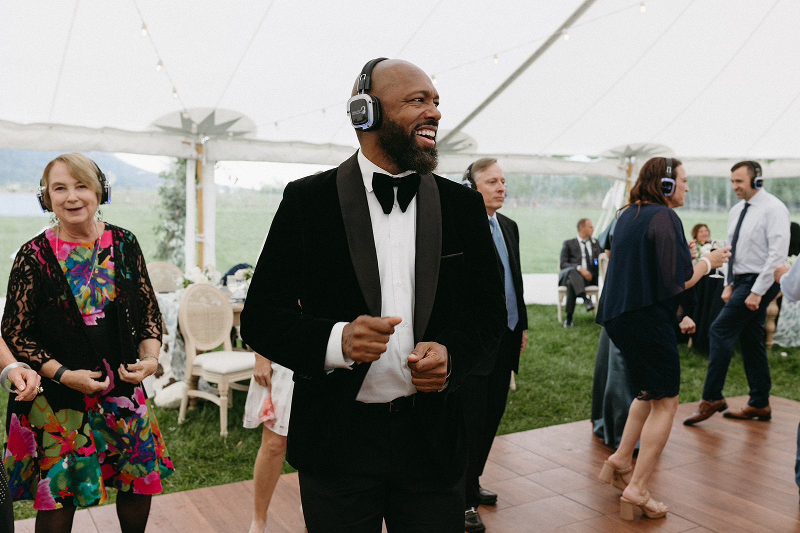 A man in a black tux and bowtie dances with other wedding guests during a silent disco reception at Snake River Ranch. 
