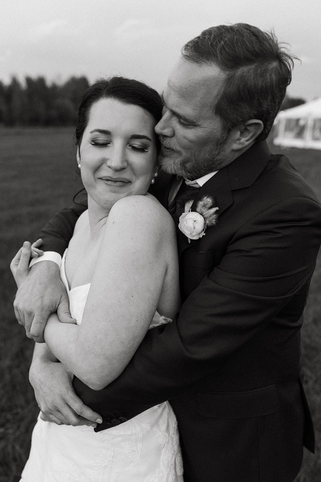 A candid portrait of a couple wearing elegant wedding attire in a field on Snake River Ranch. 