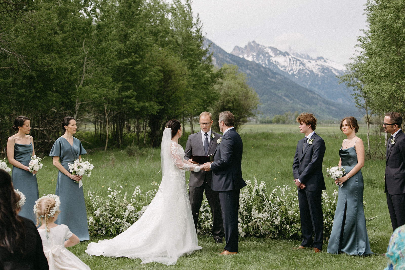  A bride and groom exchange wedding vows during an outdoor wedding ceremony on a luxury ranch in Wyoming. 
