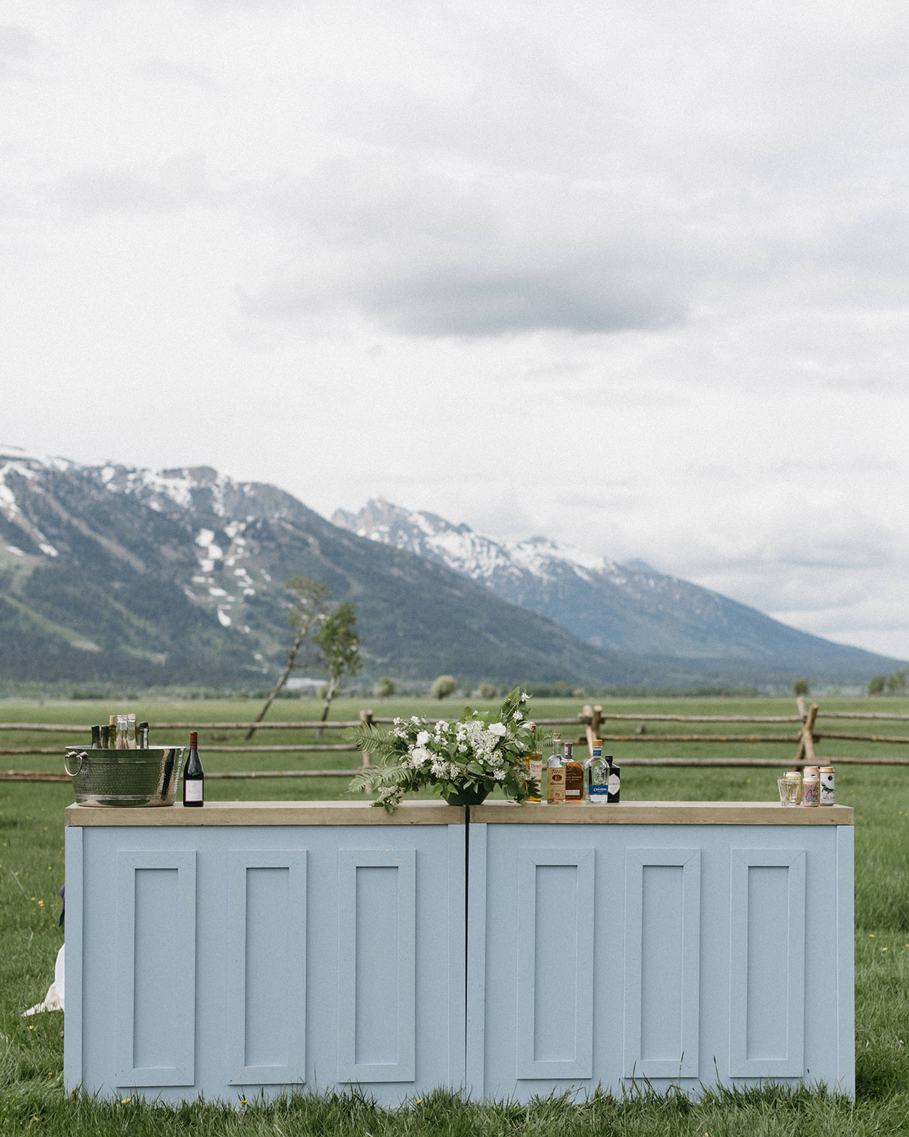 A blue wedding reception bar at a luxury wedding in Jackson Hole with the snowy Teton Range in the distance. 
