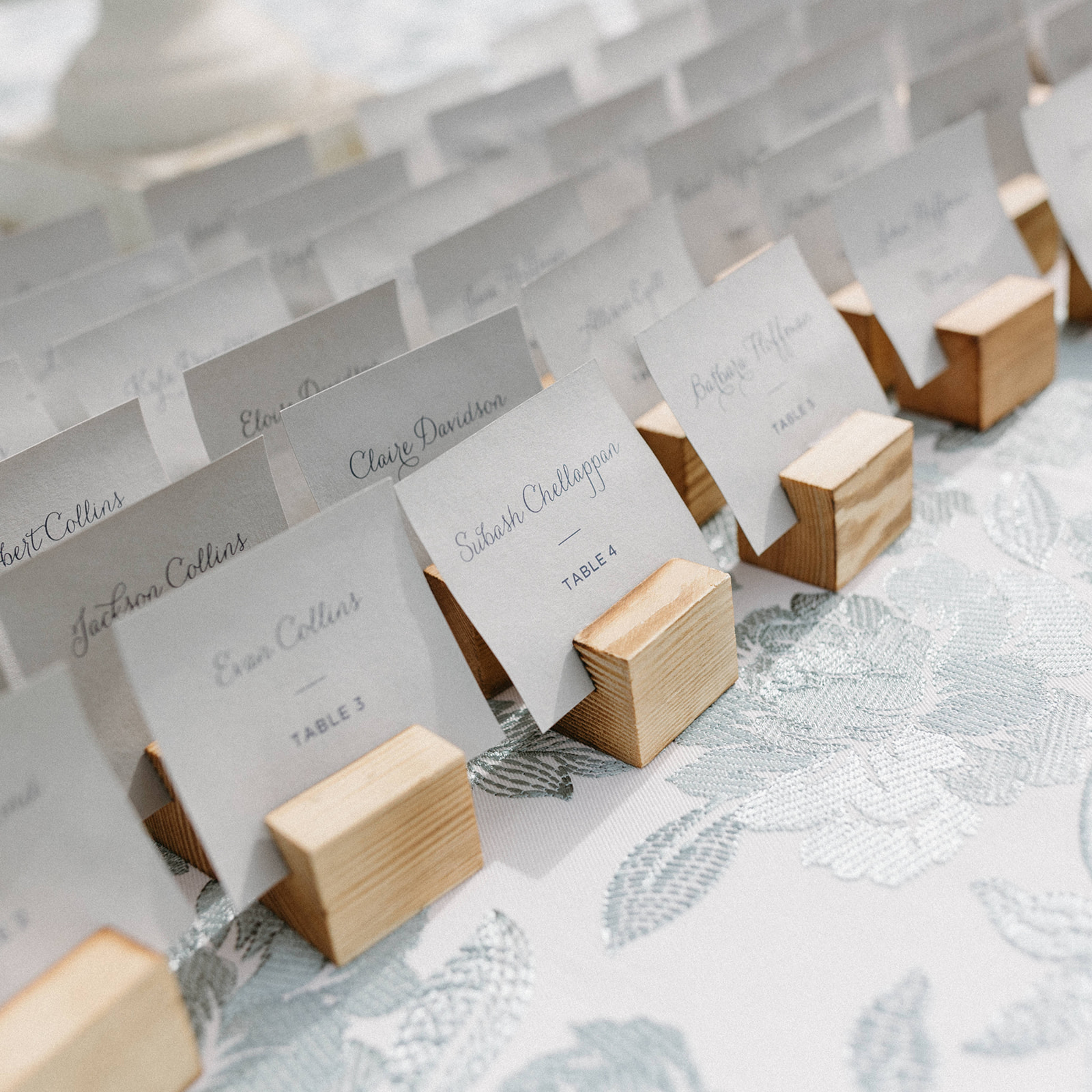White wedding reception name cards sitting in wooden holders. 
