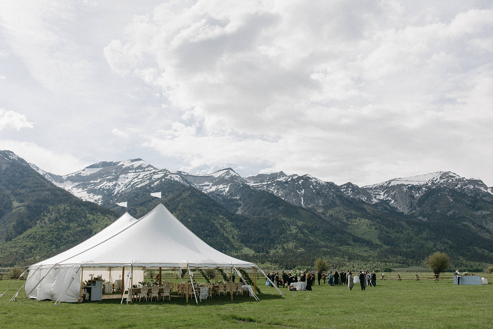 A white, luxury outdoor wedding reception rental tent with the Tetons in the distance near Jackson Hole, Wyoming.
