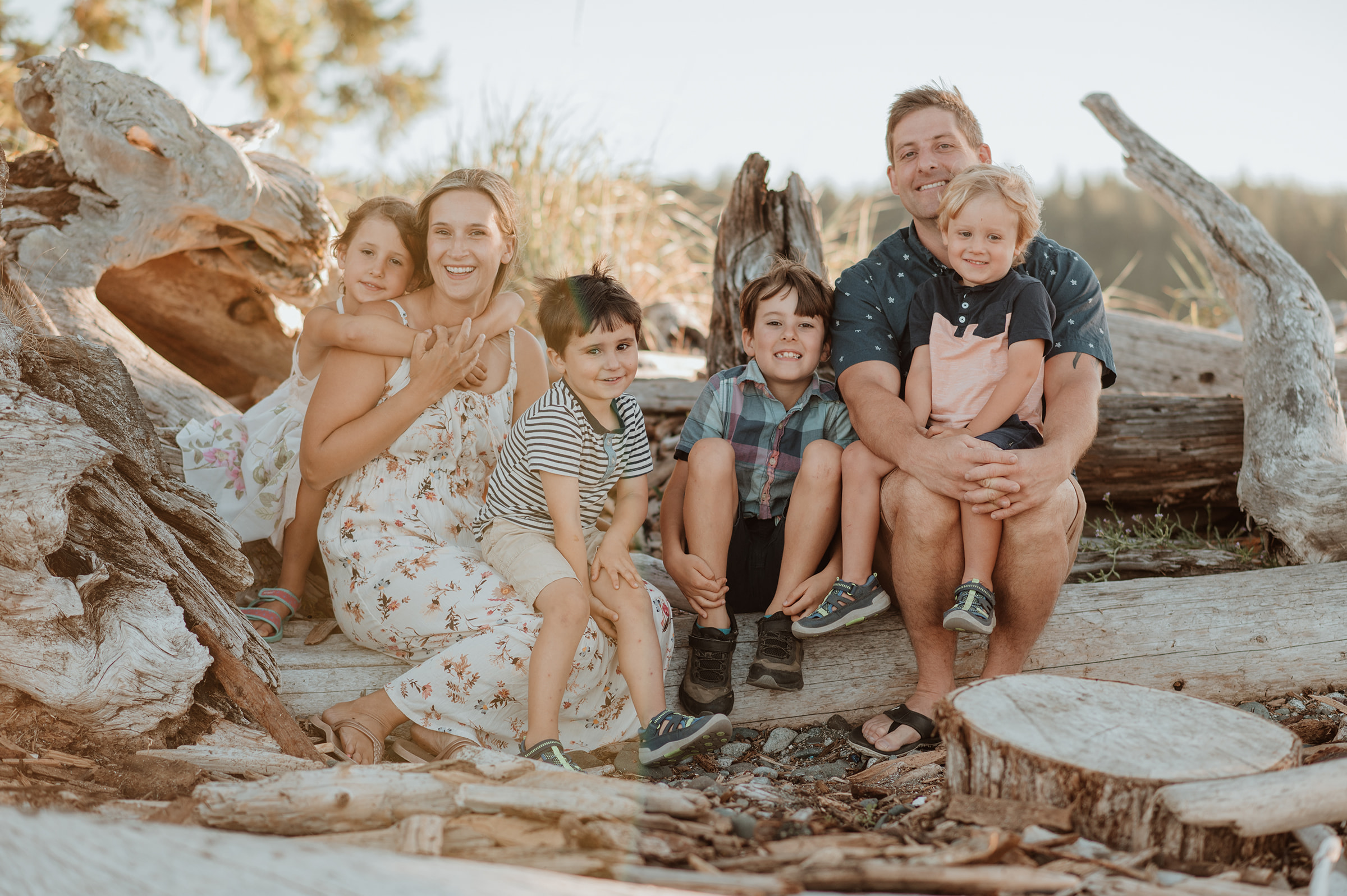 Family of six sitting on logs on Vancouver island at a family photography session