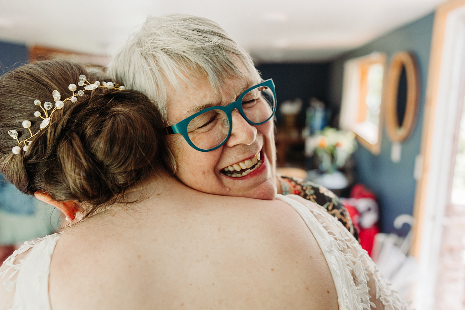 An emotional hug between the bride and her mother, the mom smiling and resting her head on her daughters shoulder.