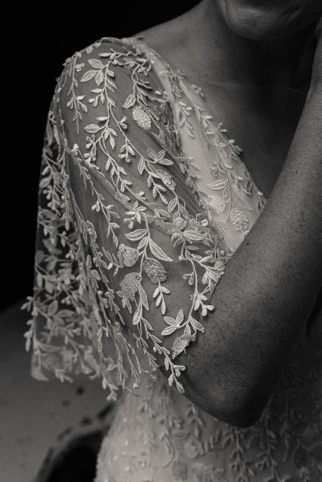 A detailed shot of the bride's wide, sheer, lace sleeve that stops at her elbow. 