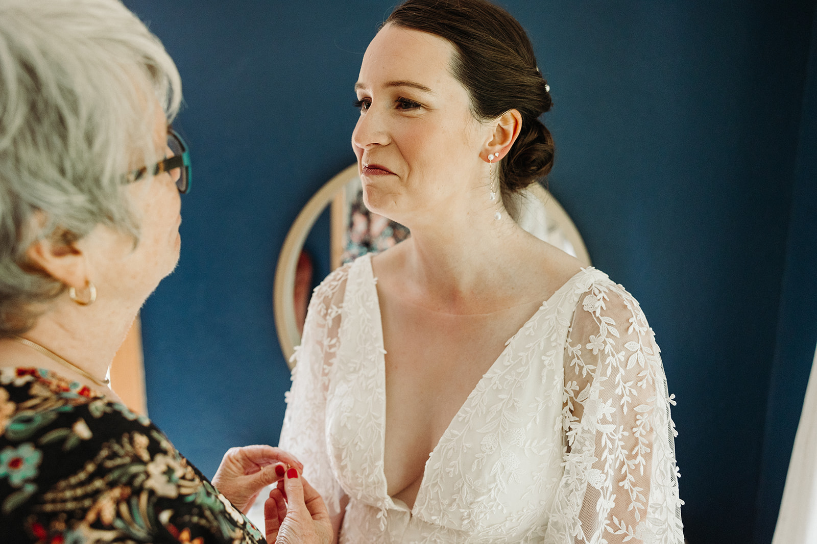 The bride and her mom having a sweet moment, holding hands as they sweetly frown, trying to hold back happy tears.