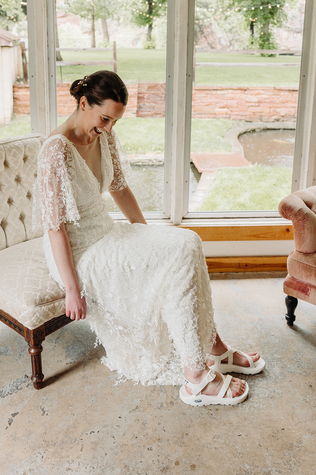 A bride smiles gleefully as she admires her custom chacos, knowing her wedding-day outfit is perfect.