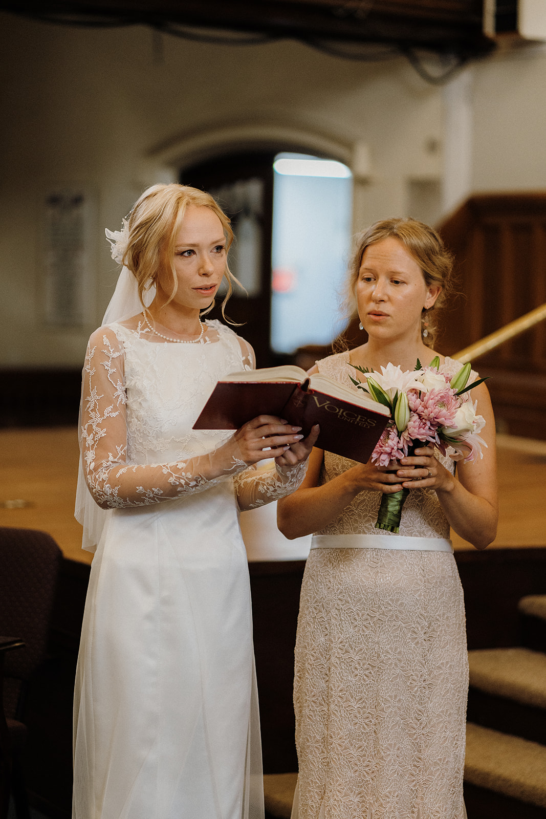 Bride holding a book next to her bridesmaid.