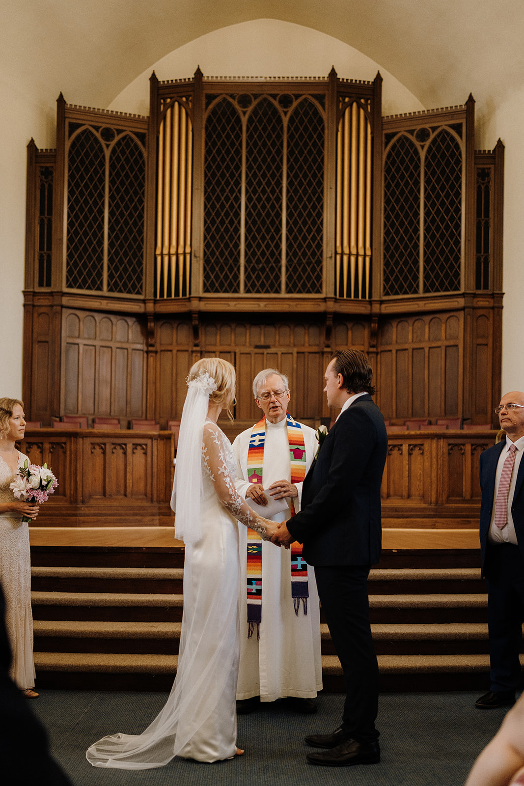 Man and woman standing in front of each other before the officiant.