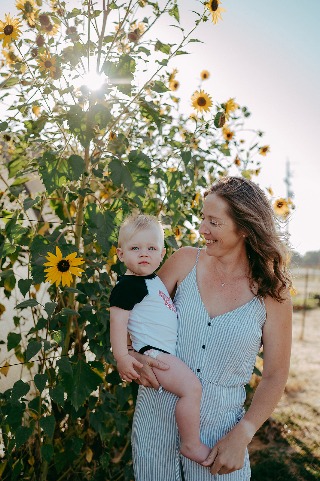 Mother and baby smiling in front of sunflowers in Petaluma, California