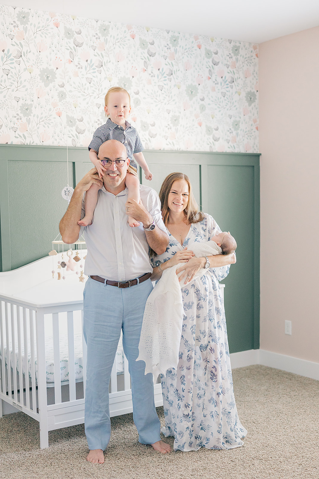 family with newborn baby girl in nursery with floral wallpaper
