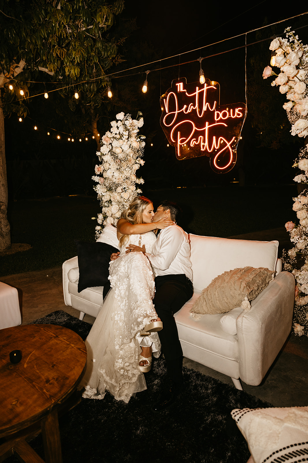 Bride & groom kiss under their "til death do us party" neon sign during their reception at Acre Resort in Cabo