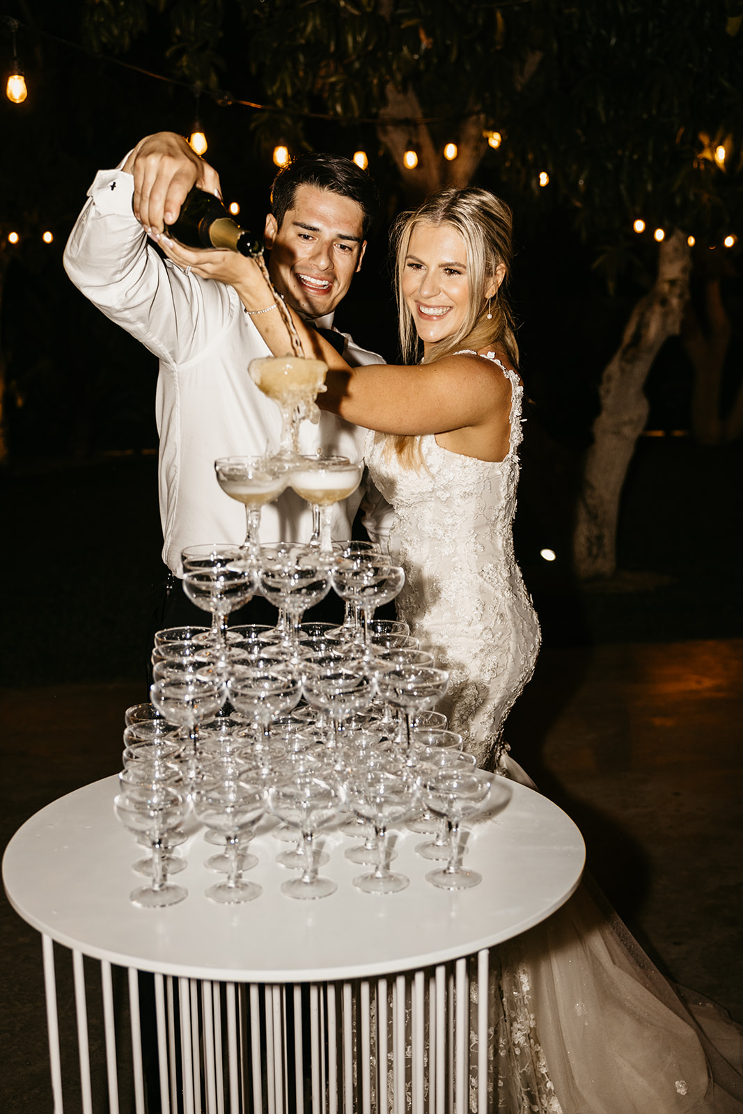 Bride and groom pour a champange tower during their wedding reception at Acre Resort in Cabo San Lucas Mexico