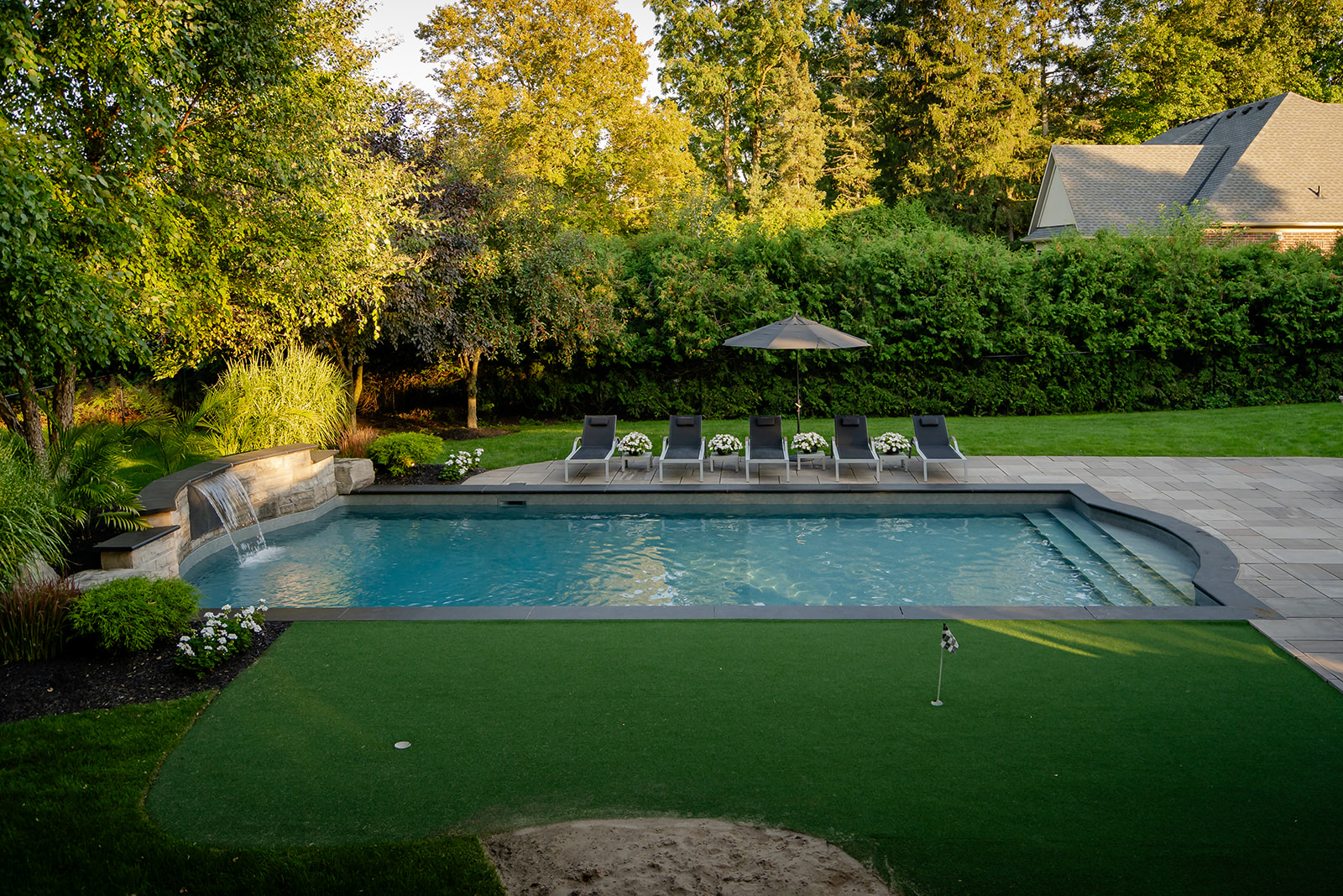 An inground pool with lawn chairs beside the pool.