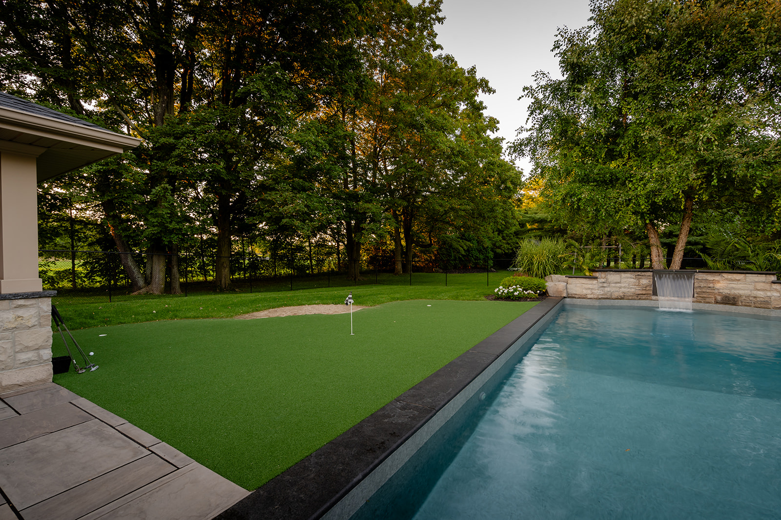 An inground pool with a mini golf course to the left of the pool.