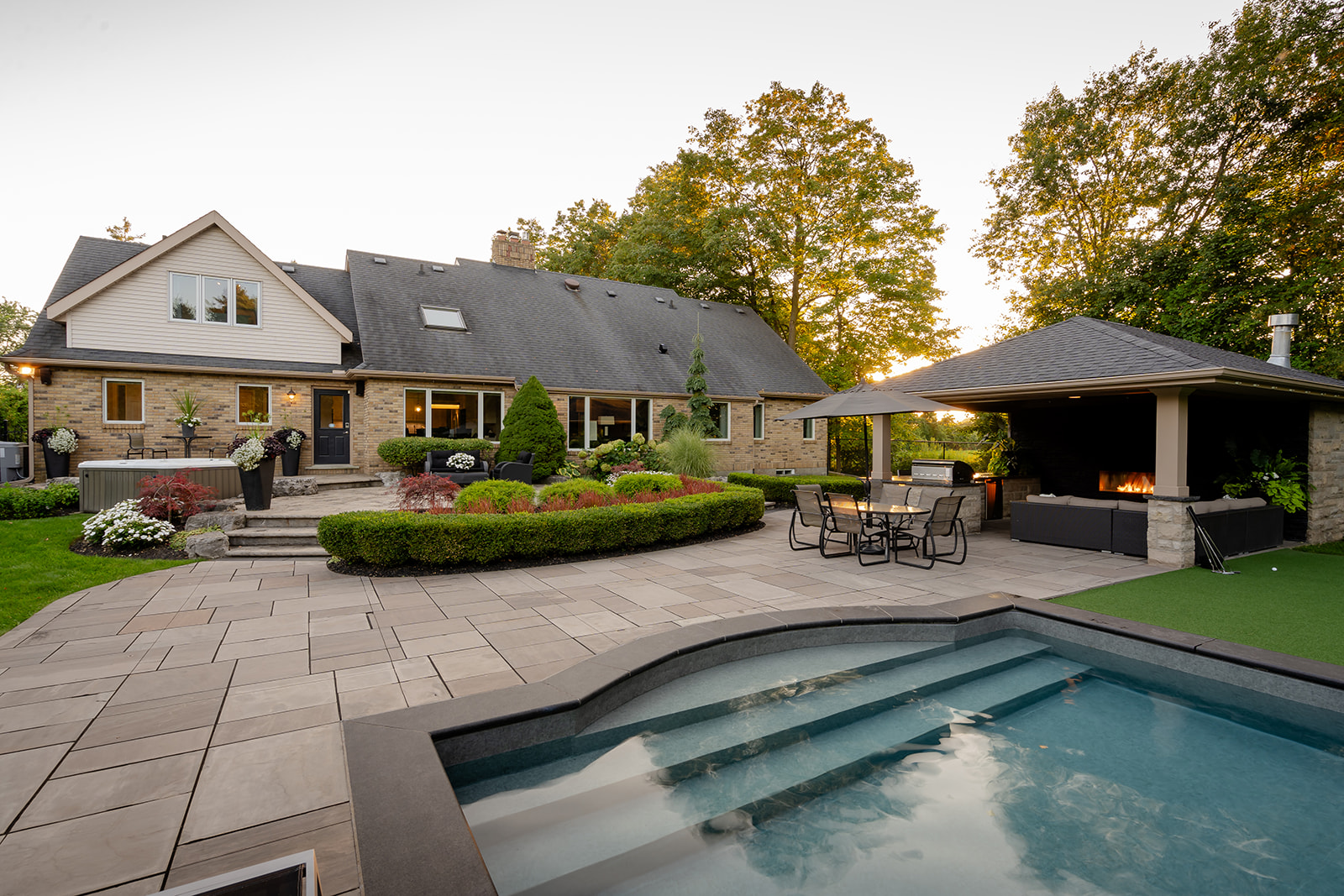 An inground pool with an outdoor patio set with the house in the background.
