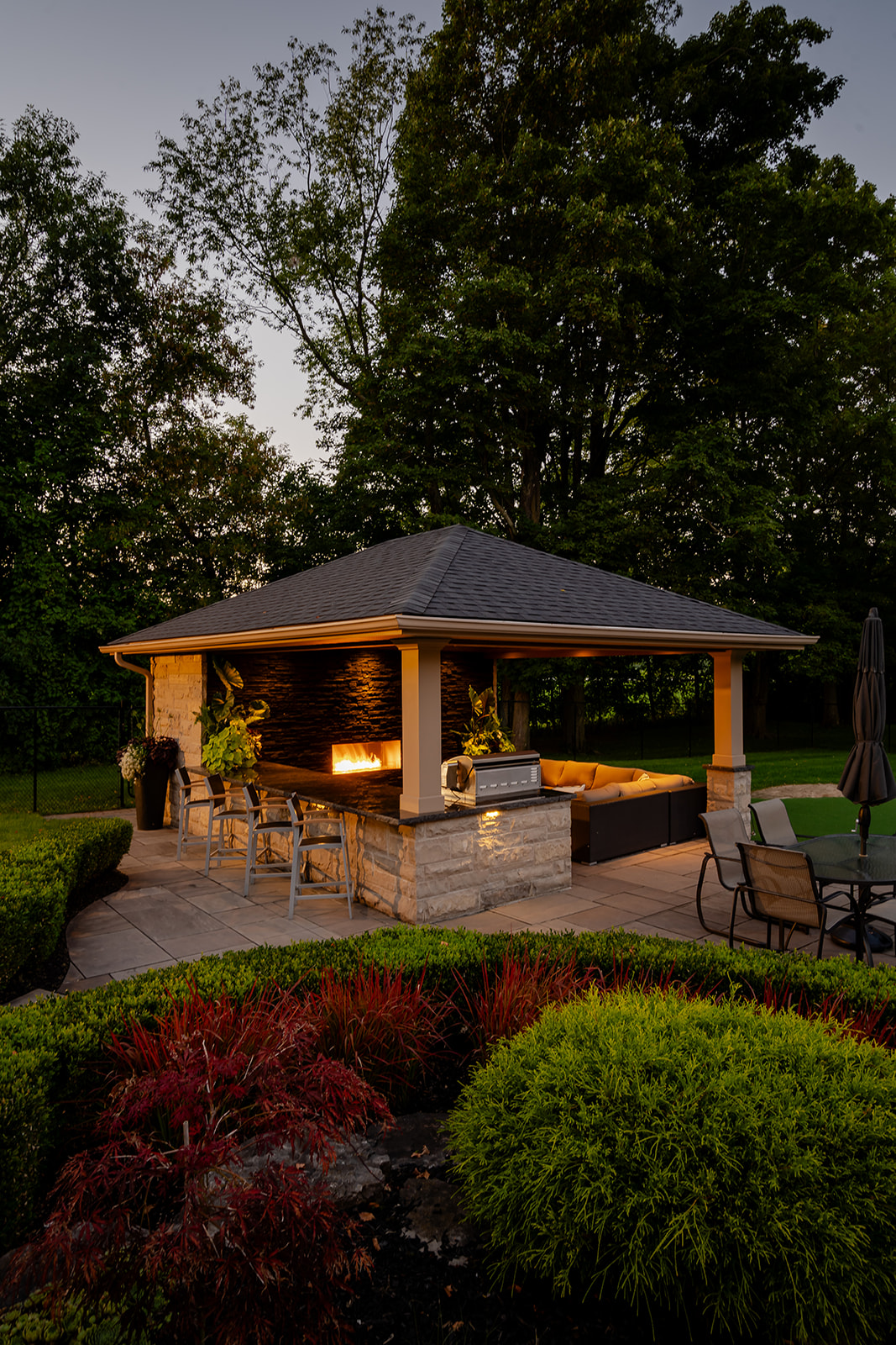 An outdoor patio set with lights on underneath the gazebo.