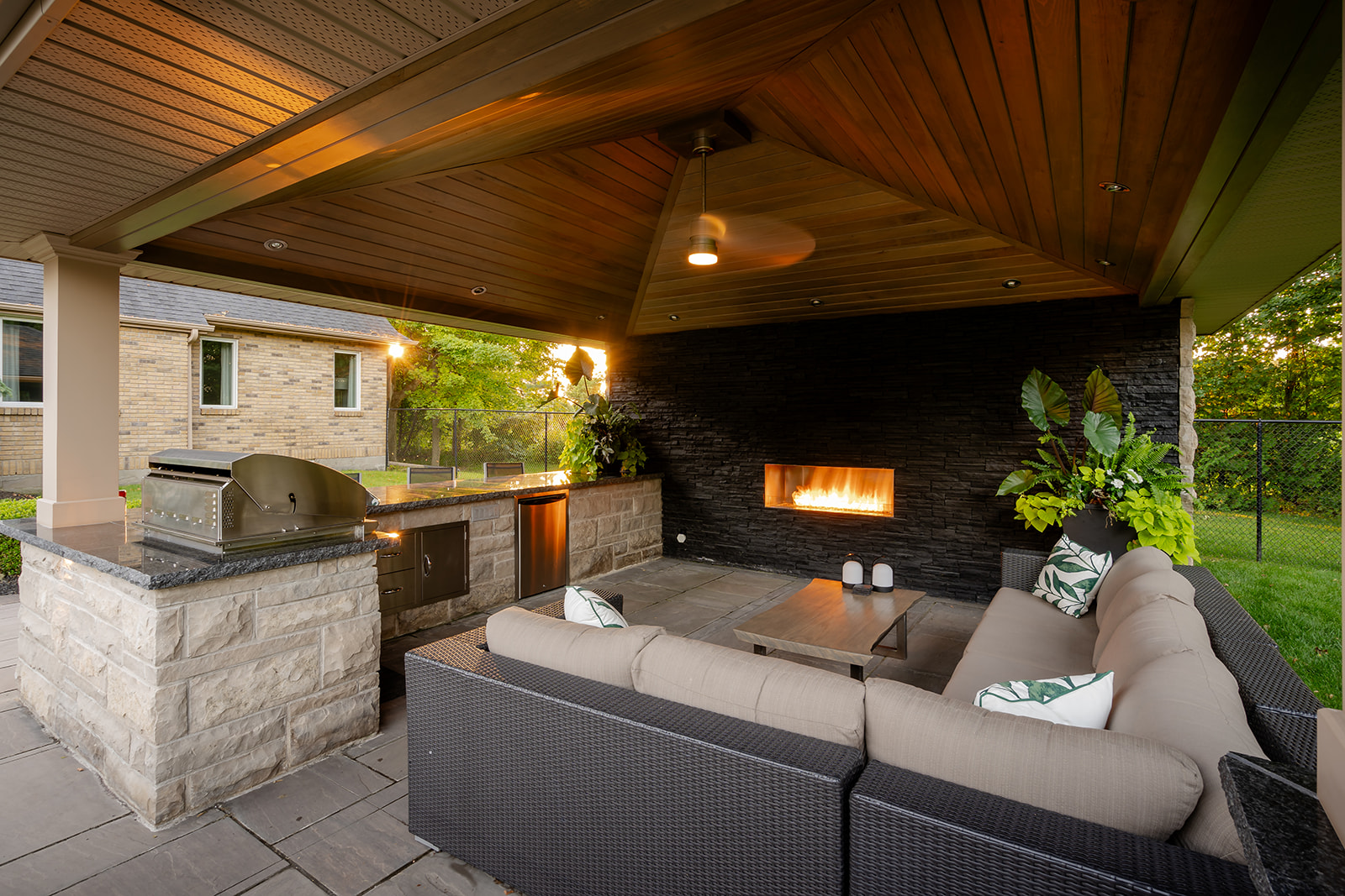 An outdoor patio set with the fireplace on in the wall of the gazebo.