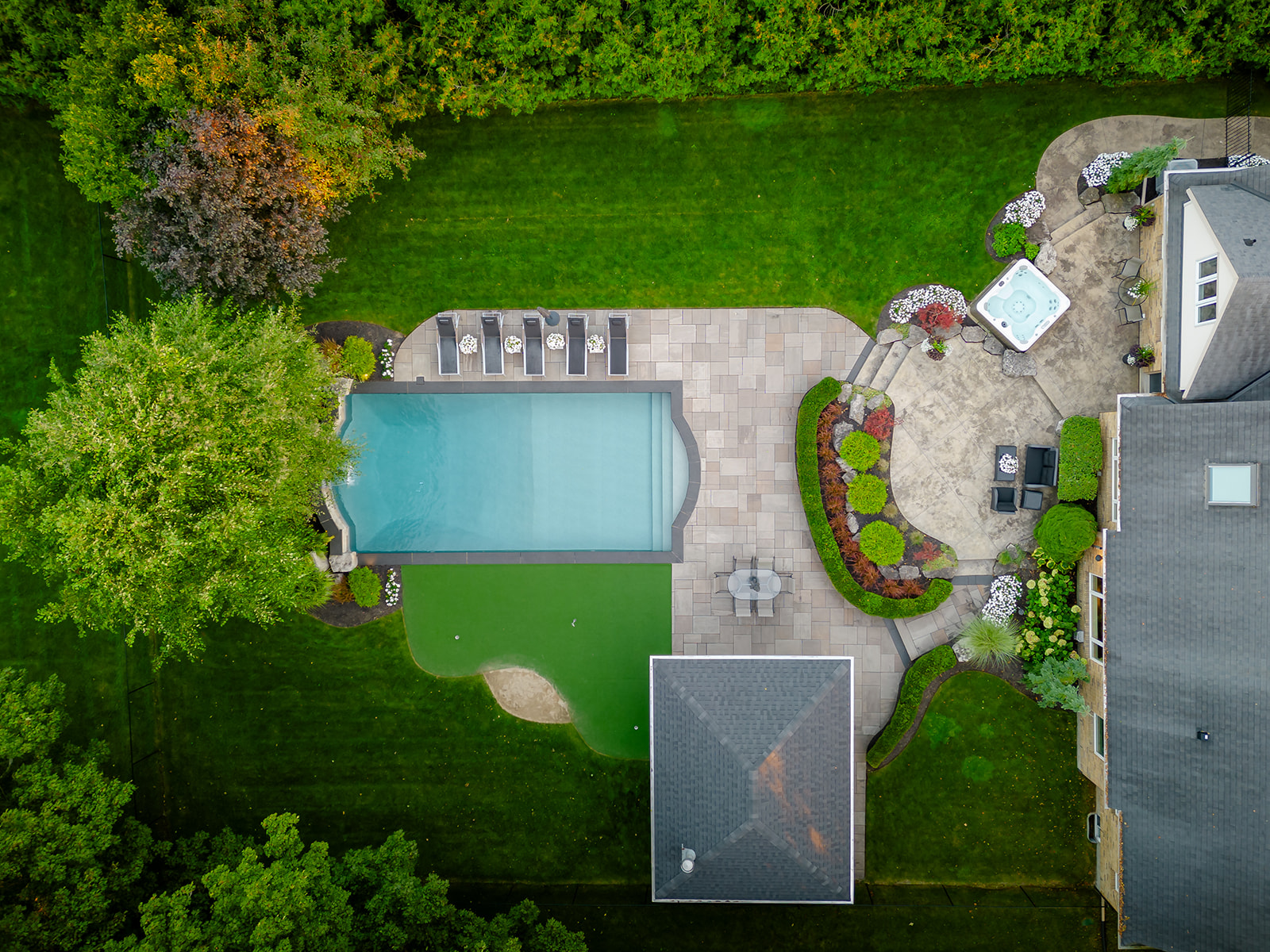 A top-down view of the backyard with an ingorund pool.