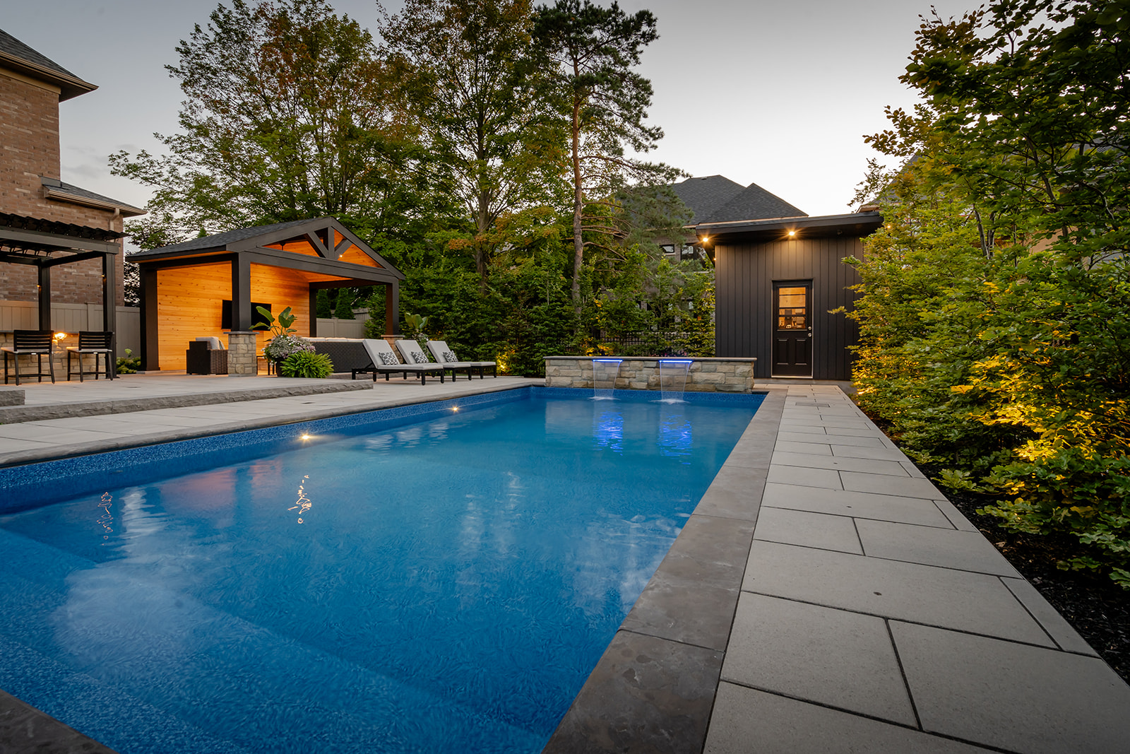 An inground pool with patio stones and two mini waterfalls flowing into the pool.