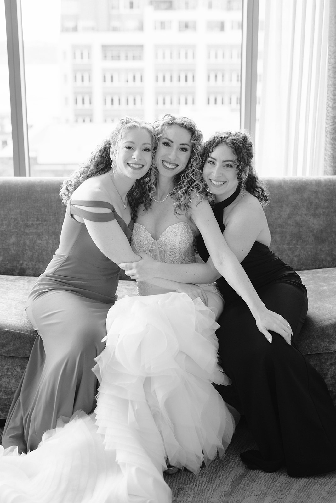 bride sits between two women and puts her hands on them