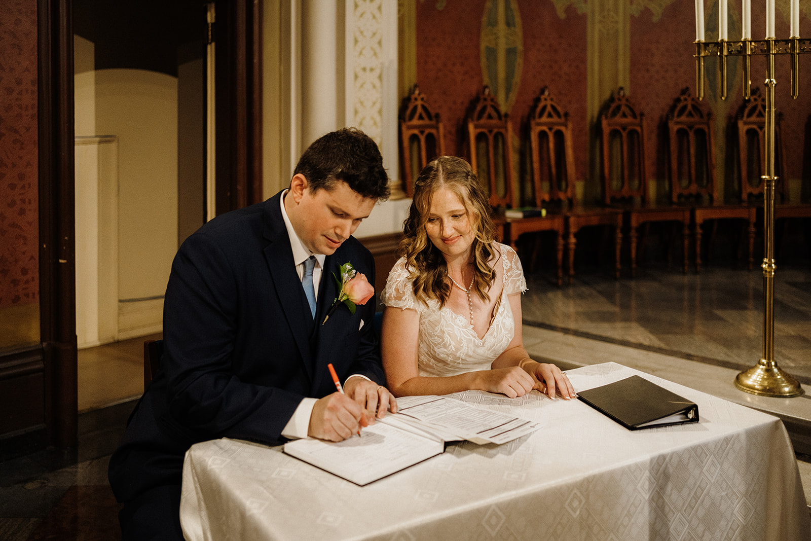 Bride and groom sign papers.