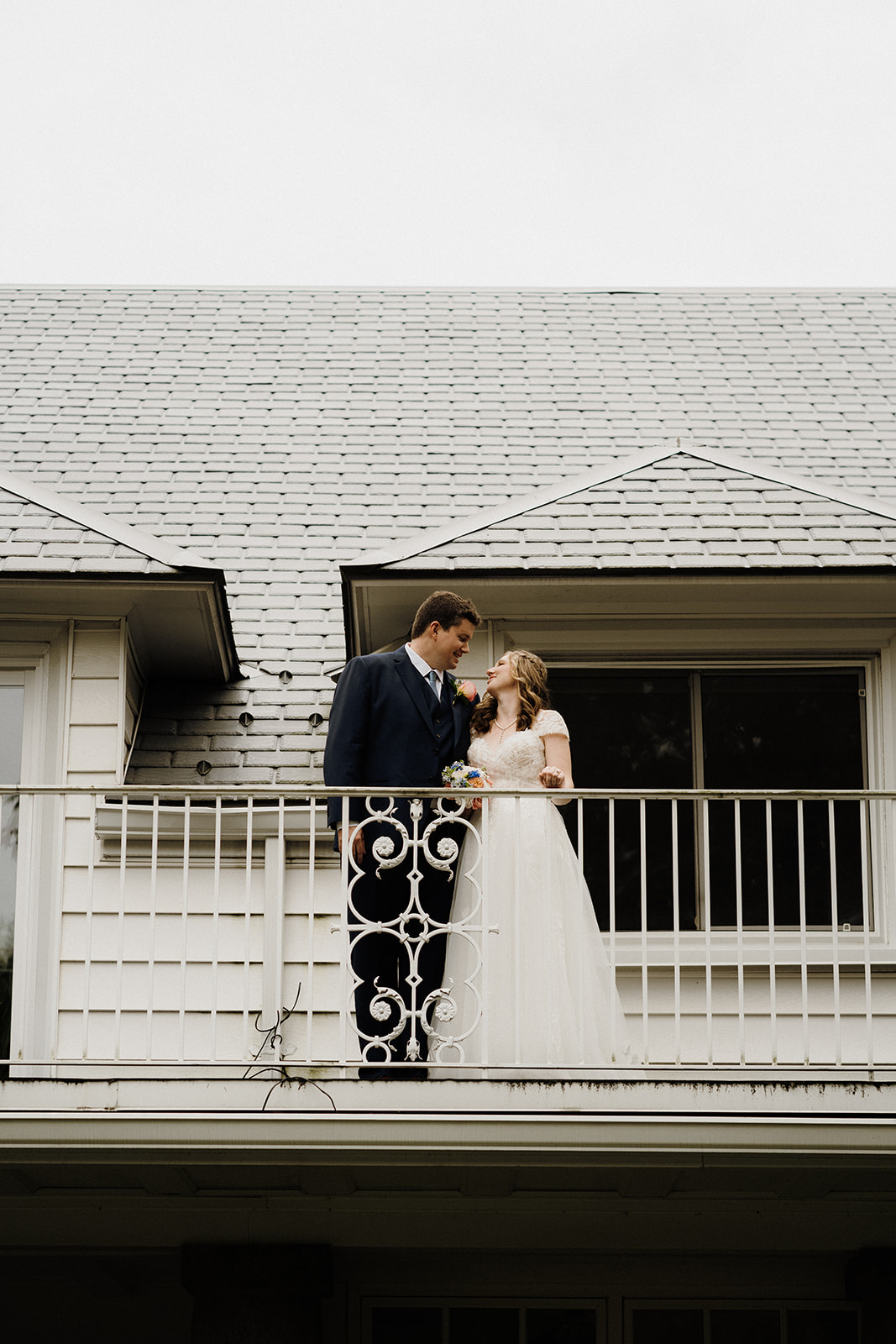 A bride and groom standing on the porch outside.