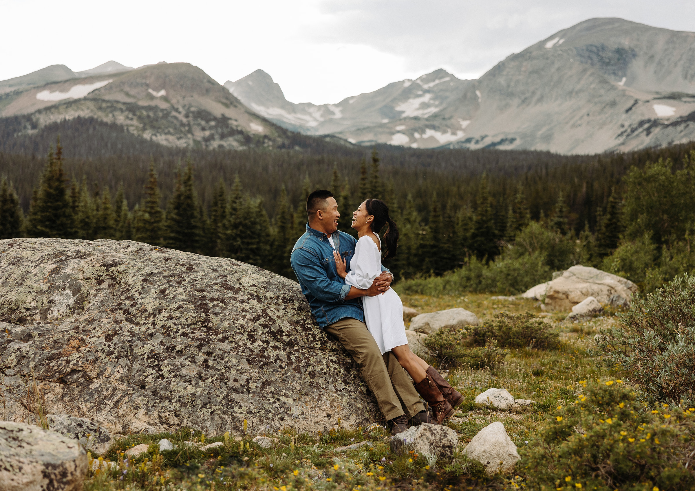 The two embrace on a huge rock on the forrest clearing with the mountains taking up the whole background behind them.