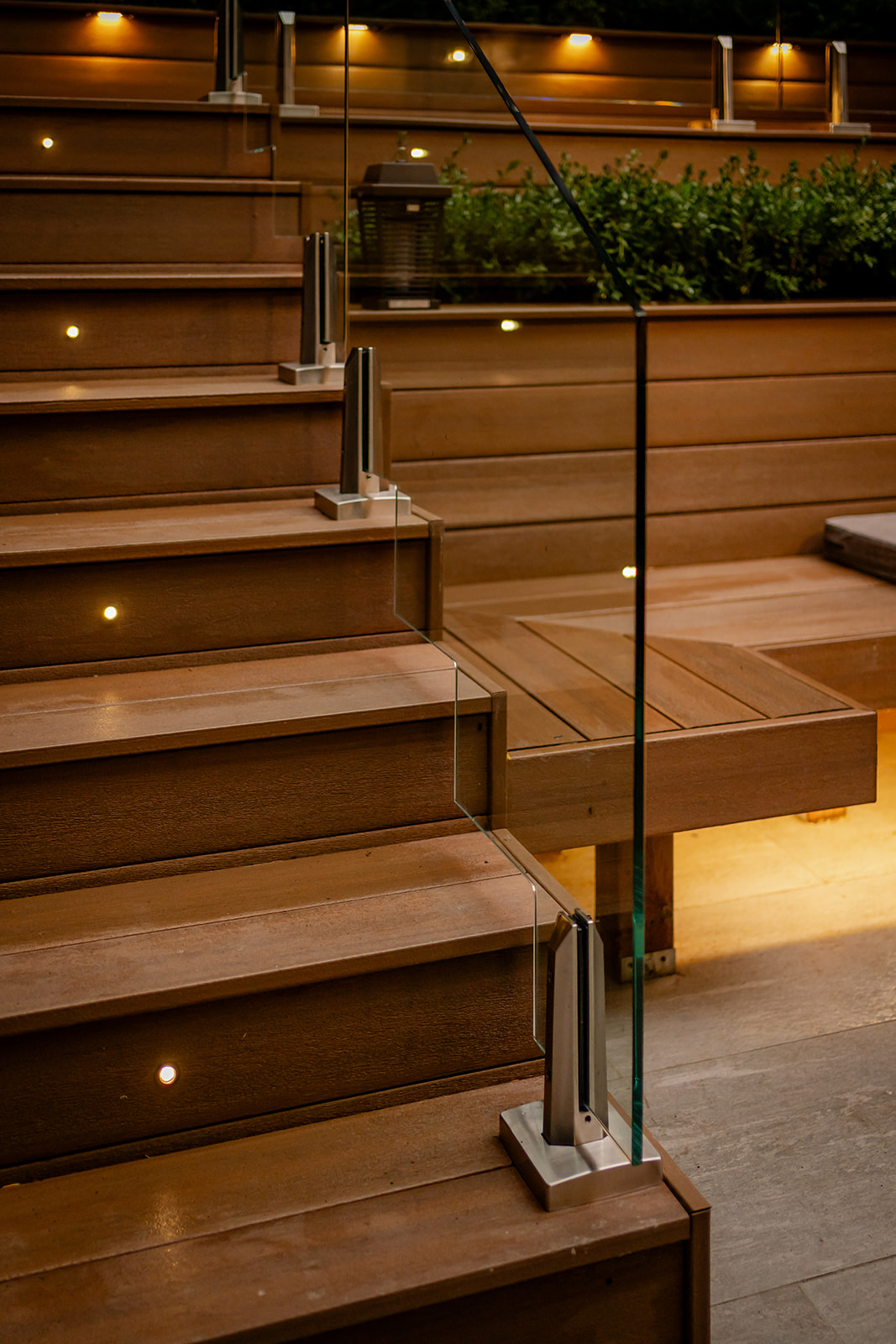 Stairs leading up with lights on every other step with glass railing.
