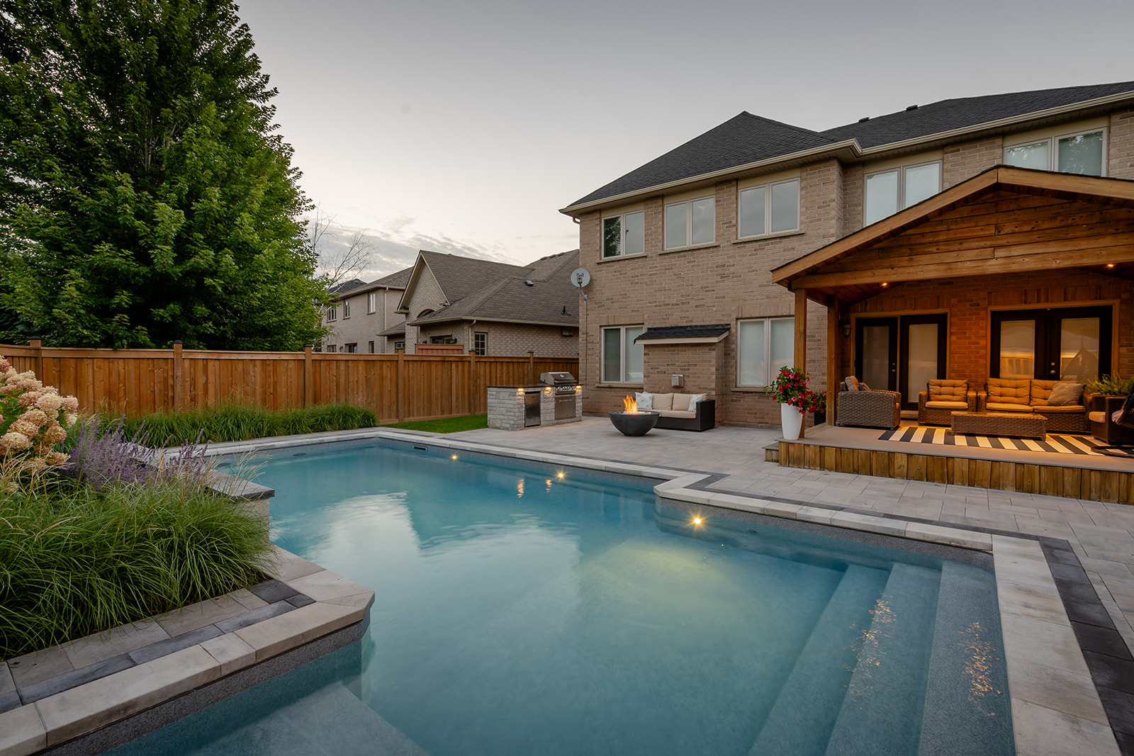 An inground pool with a fireplace on the far side of the backyard.