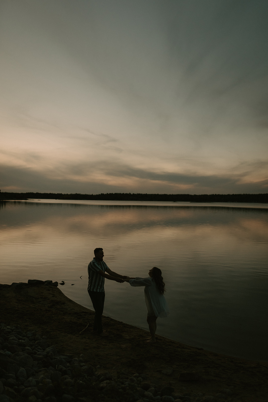 couple holding hands at sunset by the lake