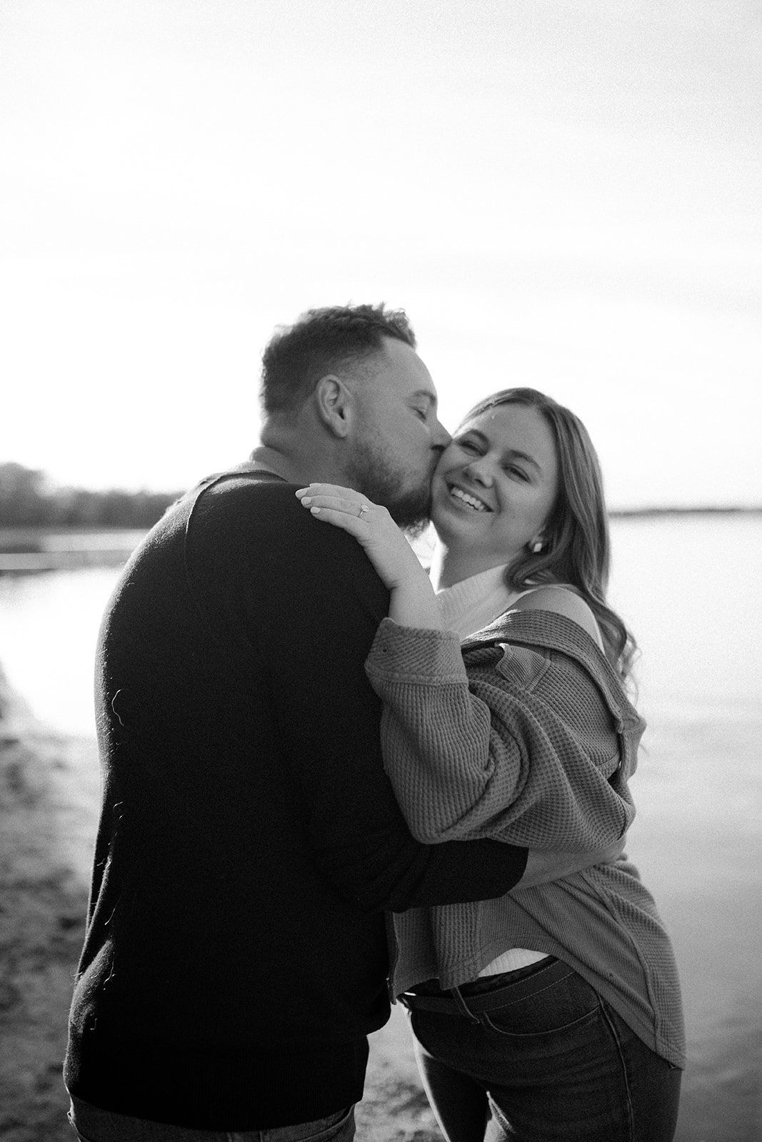 engagement session couple kissing on the cheek at the lake