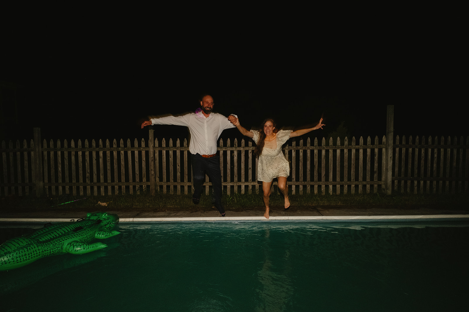 bride and groom jump in pool