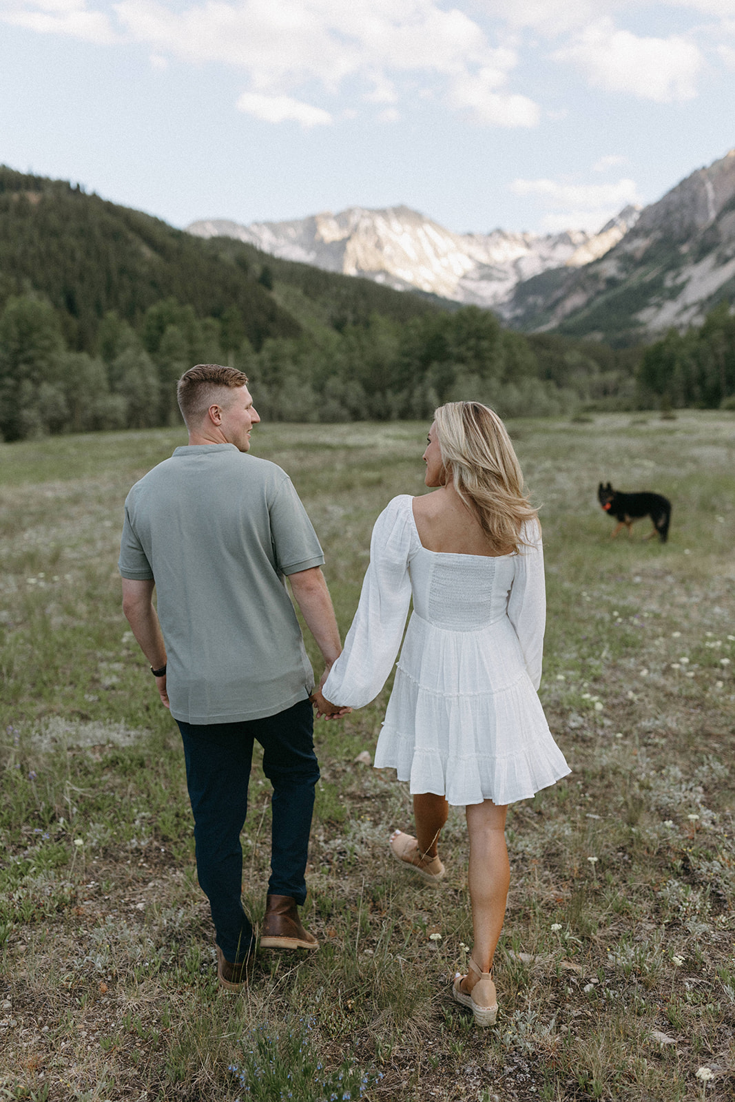 An engaged couple walks through a wildflower meadow in Colorado as a photo is captured by an Aspen Wedding Photographer.