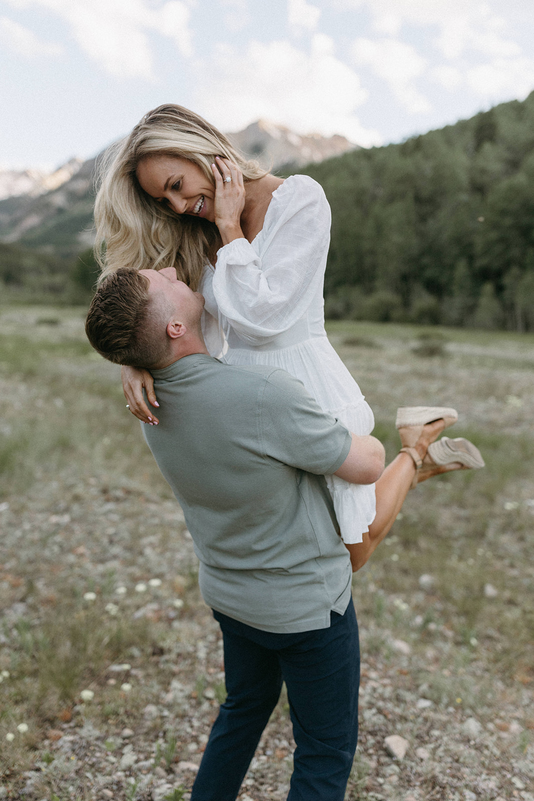 A man lifts up his fiancée in an embrace during their wildflower engagement session in Aspen, Colorado. 