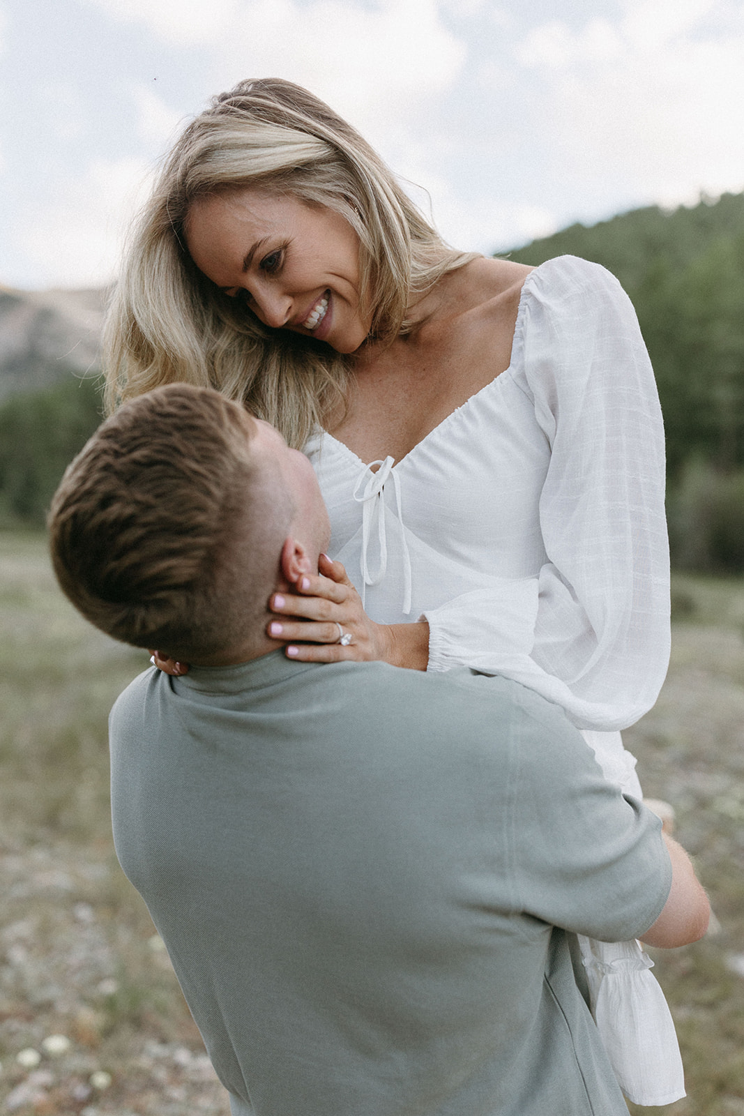 A couple dressed in earthy-toned engagement outfits embraces during their Aspen engagement session in Colorado.