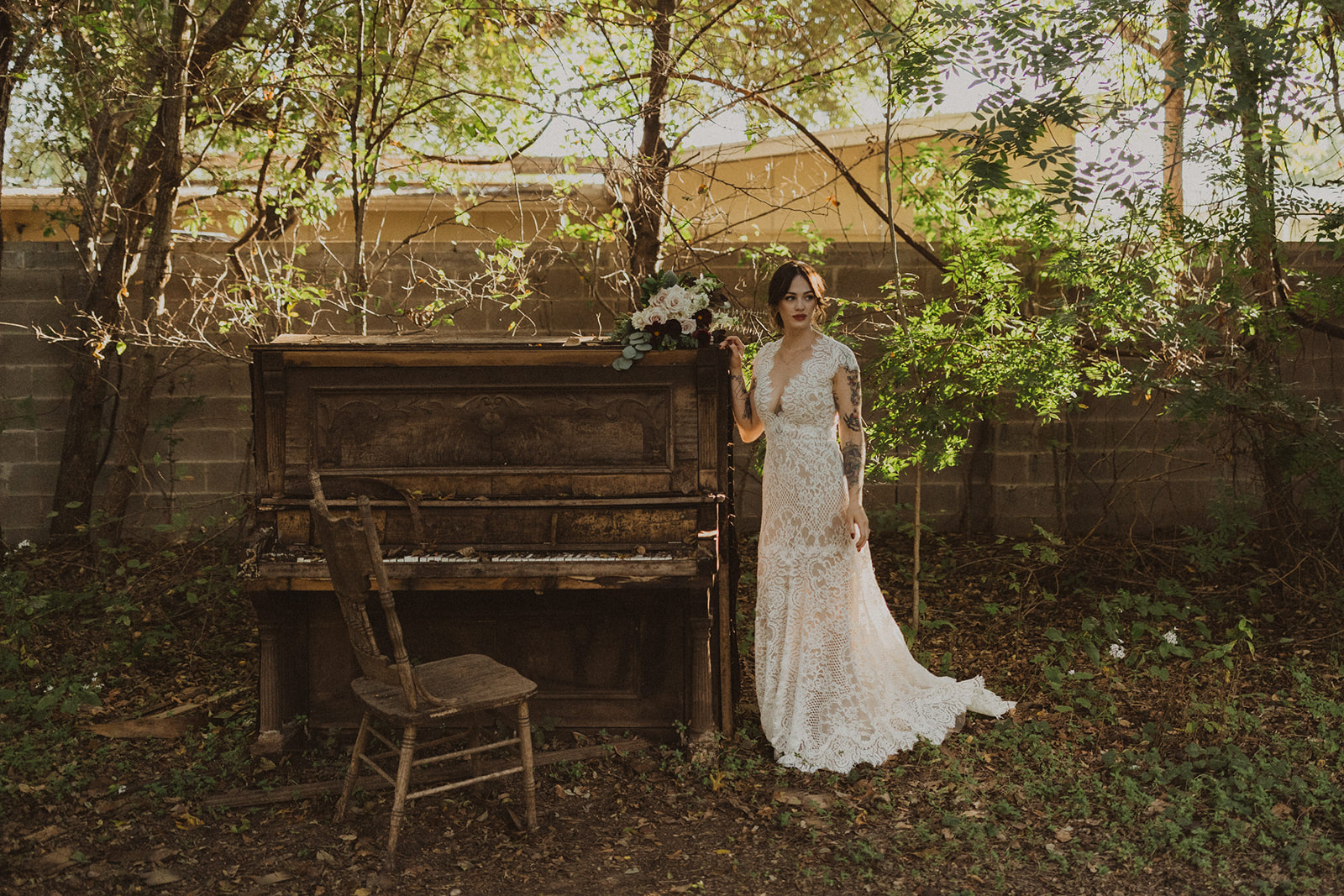 bride stands beside outdoor piano in garden