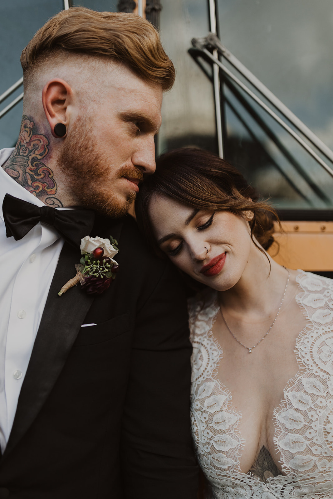 couple poses beside school bus at outdoor wedding