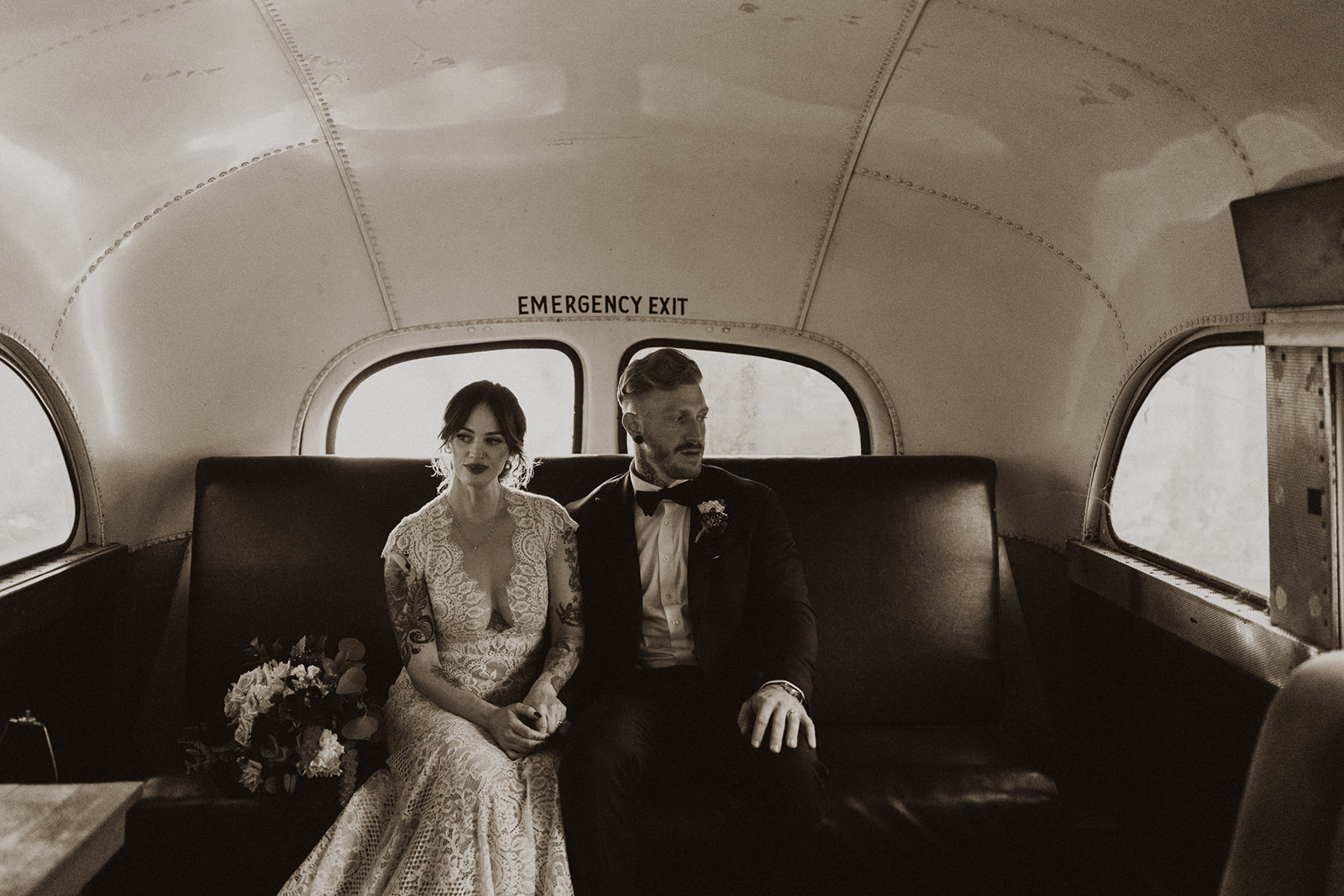 couple sits in school bus at outdoor wedding