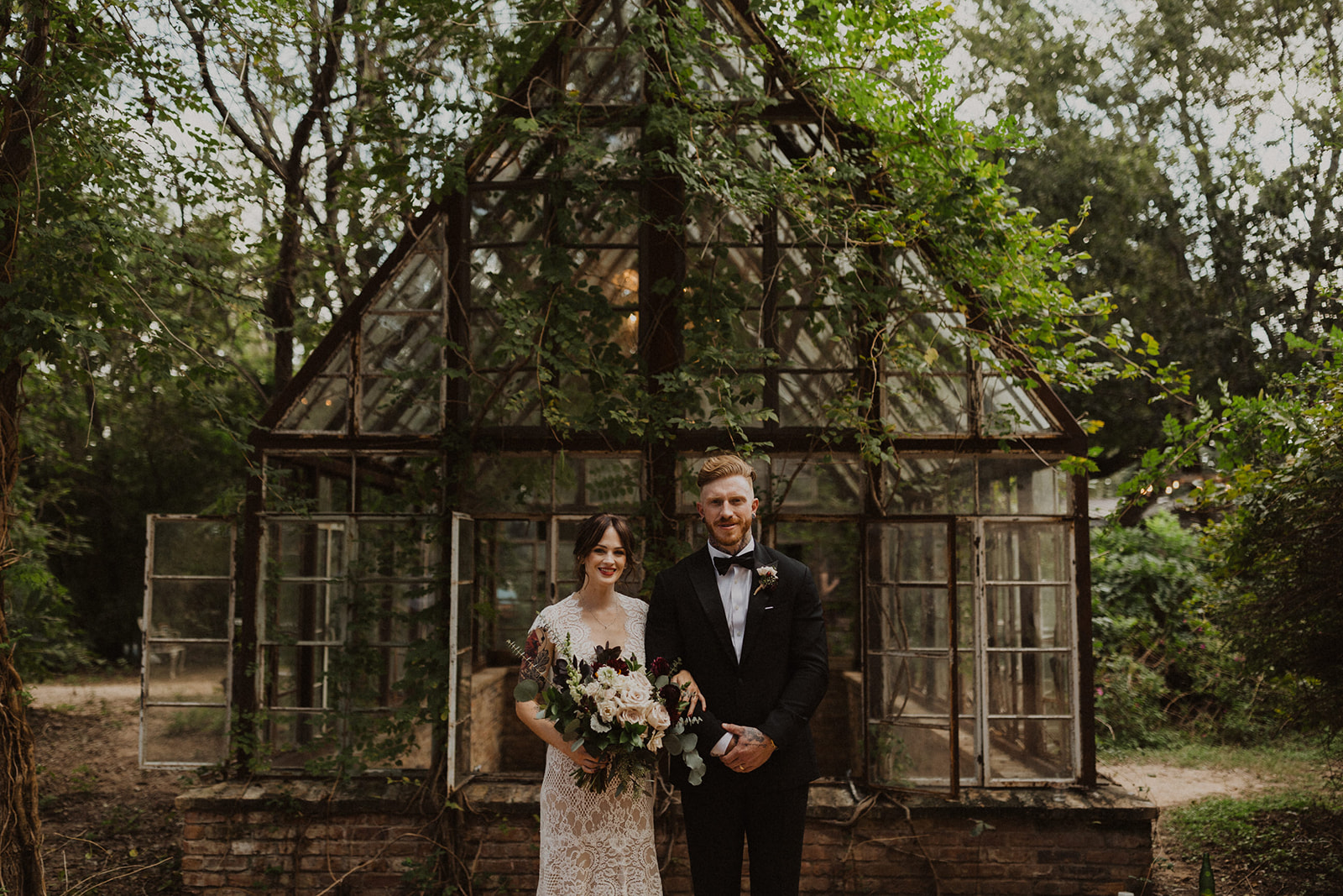 couple stands beside vintage greenhouse at Sekrit Theater wedding